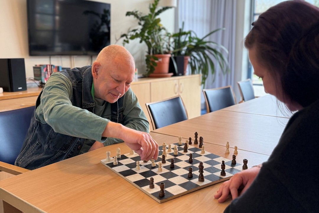 Älterer Mensch spielt mit Pflegepersonal Schach